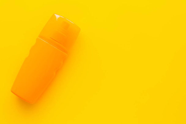 Draufsicht auf Flasche Sonnenschutz auf gelber Oberfläche  - Foto, Bild