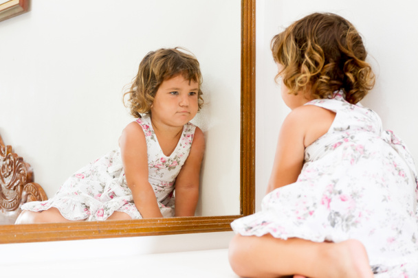 małym dzieckiem piękne dziewczyna patrząc na siebie w lustro w domu - Zdjęcie, obraz