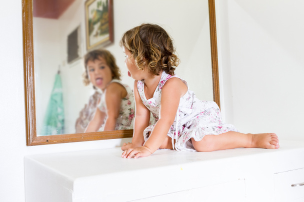 małym dzieckiem piękne dziewczyna patrząc na siebie w lustro w domu - Zdjęcie, obraz
