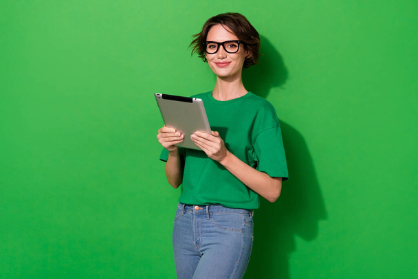 Photo of smart clever woman wear casual t-shirt eyeglasses reading modern device isolated green color background. - Foto, Bild