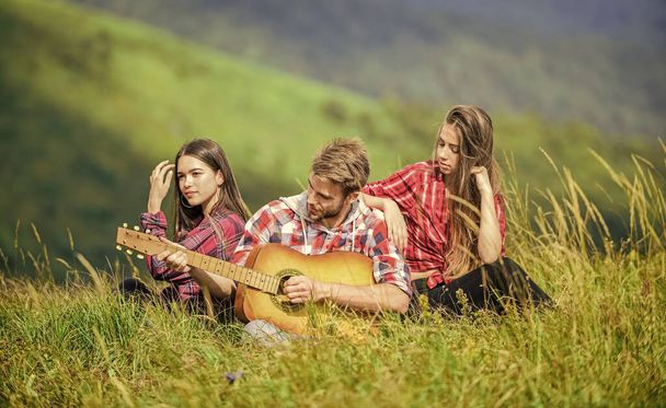 Melody of nature. Hiking tradition. Friends hiking with music. Singing together. Musical pause. Hiking entertainment. People relaxing on mountain top while handsome man playing guitar. Peaceful place. - Foto, imagen