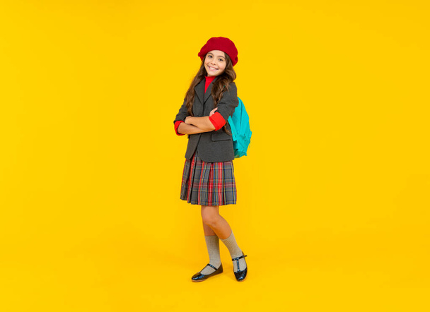 happy child with school bag. teen girl in beret carry backpack. back to school. knowledge day. concept of education. kid in uniform on yellow background. september 1. happy childhood. - Photo, image