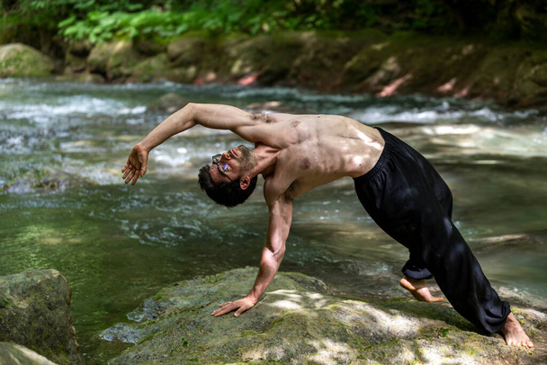 guy doing bareback yoga on the river in summer - Photo, Image