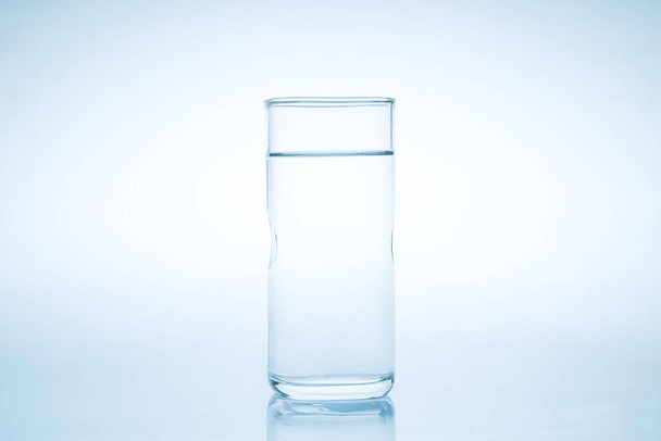 El cubo de hielo cayó en el vaso de agua.El agua salpicó del vidrio claro.Concepto fresco - Foto, Imagen