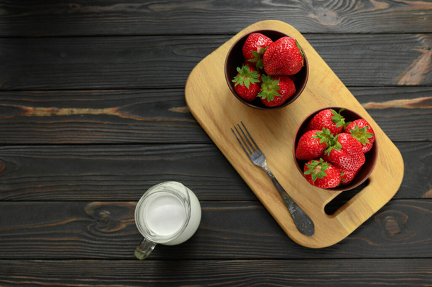 A bowl of red juicy strawberries on rustic wooden table. Healthy and diet snack food concept. - Photo, Image