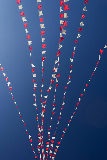 Einige Reihen von Fahnen in weiß und rot, mit blauem Himmel im Hintergrund. - Foto, Bild