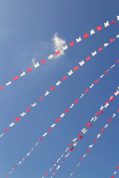 白と赤の旗のいくつかの行は、背景に青い空にぶら下がっている. - 写真・画像