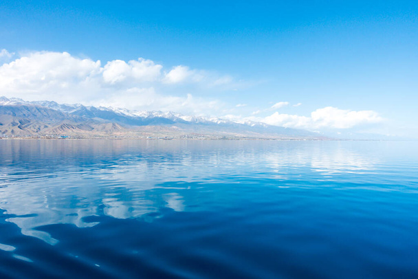 Sverny shore of Lake Issyk-Kul, Kyrgyzstán. Pohled z lodi na břeh. Modrá voda z horského jezera. Přírodní krajina. - Fotografie, Obrázek