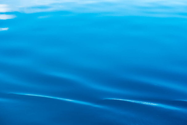 Textura de agua clara en azul y naranja. Fondo del océano y el mar retroiluminado por el sol. - Foto, Imagen