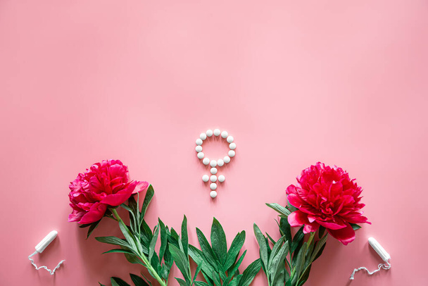 Символ половой Венеры из таблеток и лепестков пиона на розовом фоне, женский период и концепция здоровья. - Фото, изображение