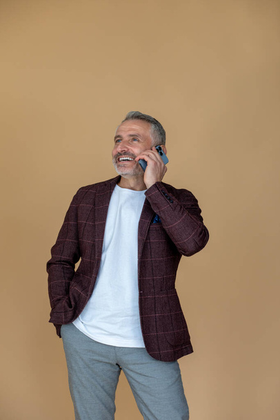 Phone call. Man in a jacket talking on the phone and looking contented - Foto, Imagen