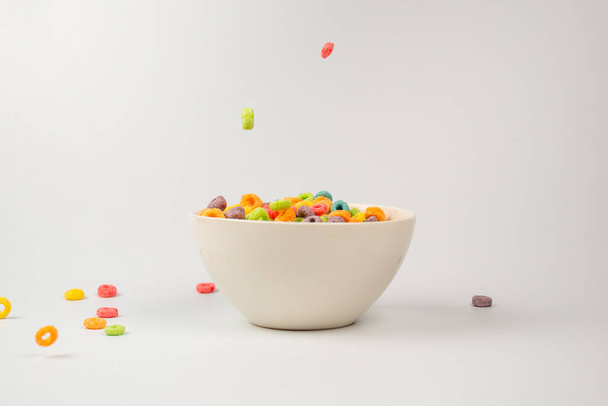 Colorful cereal box for morning breakfast. Corn flakes falling to the white bowl. Motion. Copyspace. - Foto, afbeelding