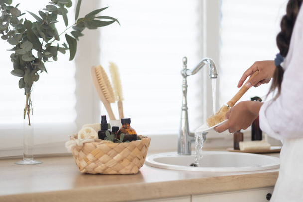 Woman washing dishes with detergent on kitchen. Eco brush with foam and basket on white bright kitchen - Foto, Bild