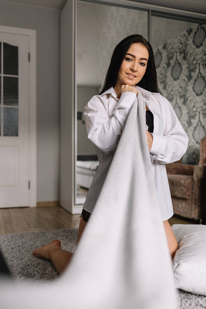 Κορίτσι τυλιγμένο σε μεγάλη μάλλινη κουβέρτα Μερίνο κάθεται στο κρεβάτι - Φωτογραφία, εικόνα