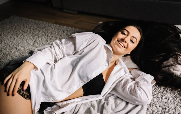 Entspannte Frau liegt drinnen auf dem Boden und lächelt - Foto, Bild