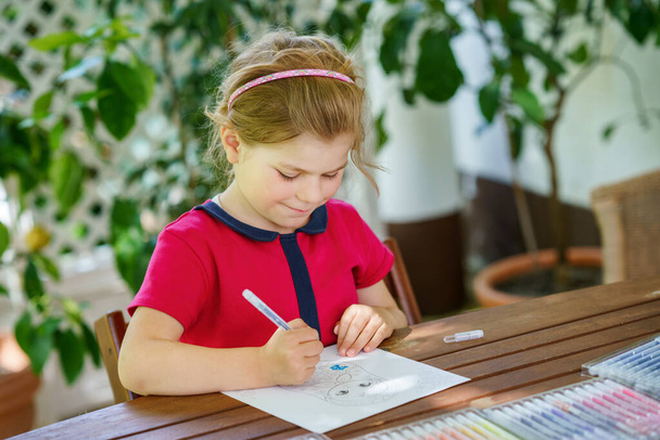 Renkli kalemler ve keçeli kalemlerle resim yapmayı öğrenen mutlu anaokulu kızı. Güneşli bir yaz gününde renkli keçeli kalemler kullanarak evde resim çizen küçük çocuk. Çocuklar için yaratıcı etkinlik - Fotoğraf, Görsel