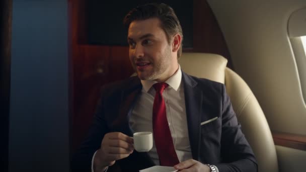 Close-up luxe zakenman reist met een privé-jet. Happy man die koffie drinkt en praat met onbekende partner op zakenreis. Succesvolle financieel analist miljonair rustend in eersteklas vliegtuig. - Video