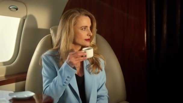 Mooie zakenvrouw vliegende vliegtuig genieten van koffie in gouden zonlicht close-up. Een overtuigd financieel analist die succesvol is met zijn man in een privéjet. Elegant dameswerk op zakenreis - Video