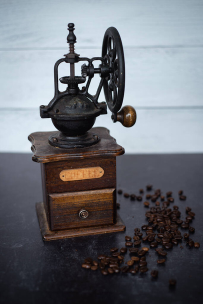 Top view of a vintage coffee grinder with beans on dark background. Depth of field. Wood and iron. High quality photo - Foto, Imagem