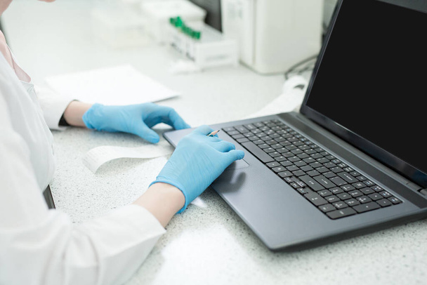 Modern technology in science. Scientist entering data of analysis results to laptop at laboratory. - Foto, Imagem