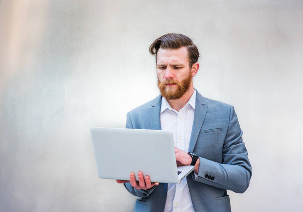 Młody amerykański Hipster Businessman z pełną brodą, pracujący na laptopie, na srebrnym metalowym tle. - Zdjęcie, obraz