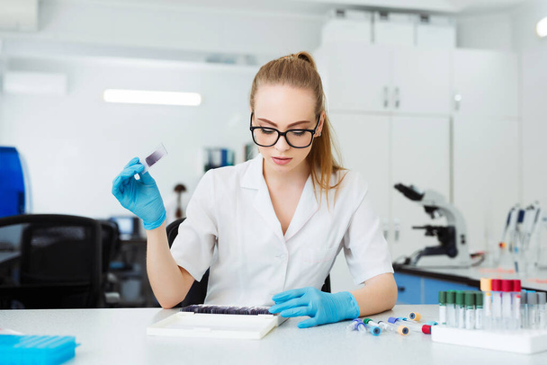 Scientist analyzing microscope slide at laboratory. Female Working in Laboratory With Microscope. Researcher examining slide. Concenrated doctor working with microscope in laboratory. - Valokuva, kuva