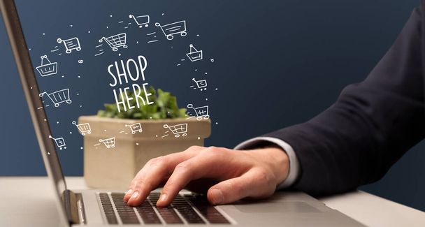 Businessman working on laptop with SHOP HERE inscription, online shopping concept - Фото, изображение