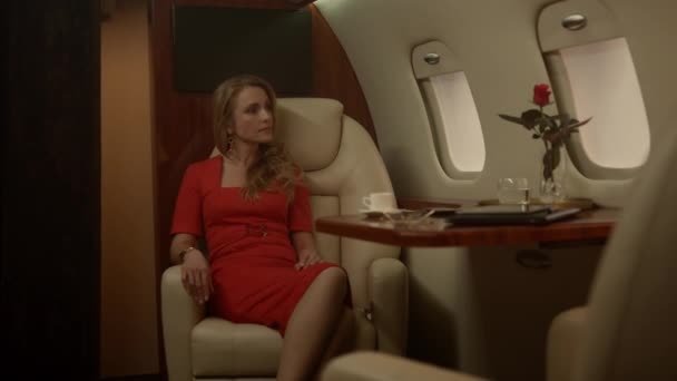 Rich woman traveling jet alone. Attractive lady drinking coffee at porthole in red dress. Confident blonde businesswoman think of successful deal vacation in first class. Wealthy lifestyle concept - Footage, Video