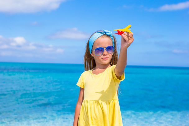 Niña feliz con avión de juguete en las manos en la playa blanca
 - Foto, imagen