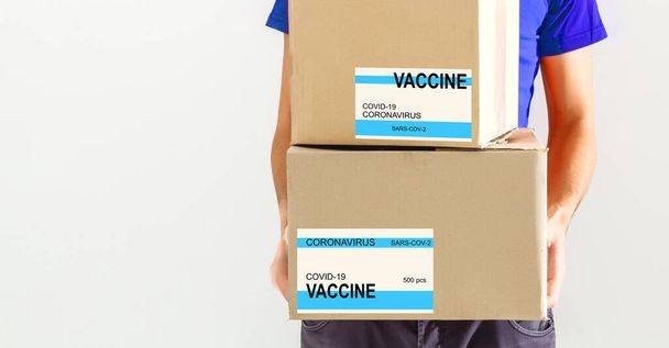 Ο άνθρωπος παραδίδει το εμβόλιο. Τοποθέτηση ετικέτας VACCINE στο κουτί από χαρτόνι. - Φωτογραφία, εικόνα