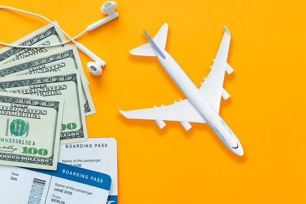 Concepto de viaje, billete de avión, dinero, auriculares sobre fondo amarillo. - Foto, Imagen