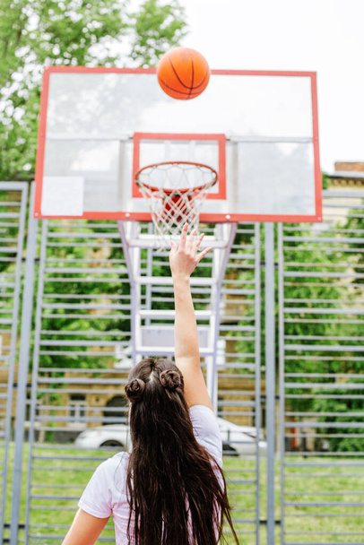 Pojęcie sportu, hobby i zdrowego stylu życia. Młoda wysportowana kobieta trenuje do gry w koszykówkę na nowoczesnym boisku do koszykówki na świeżym powietrzu. - Zdjęcie, obraz