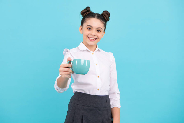 Teenage girl with cup of cappuccino coffee or tea. Child with cup on blue background, morning drink beverage - Photo, Image