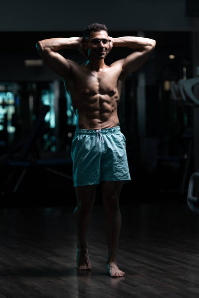 Porträt eines jungen, körperlich fitten Mannes mit Gynäkomastie-Brüste-Problem, der seinen gut trainierten Körper zeigt - Foto, Bild
