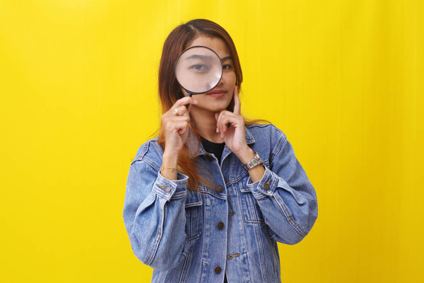 Young asian woman standing while looking through magnifying glass. Investigation concept - Photo, Image