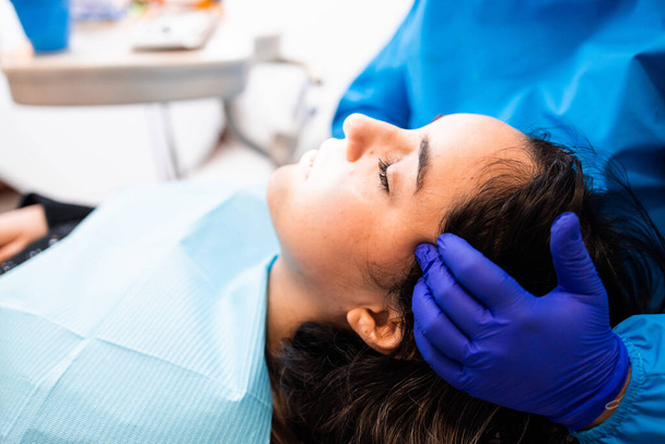 Onherkenbare tandarts doet een palpatie bij de temporalis spier. Onderzoek naar een vrouwelijke patiënt. Tandheelkundige zorg. Horizontaal. Kopieerruimte - Foto, afbeelding