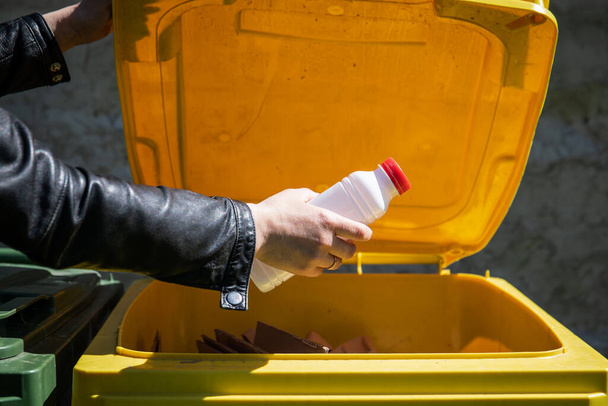 リサイクルのための廃棄物分別。黄色の容器にプラスチックボトル. - 写真・画像