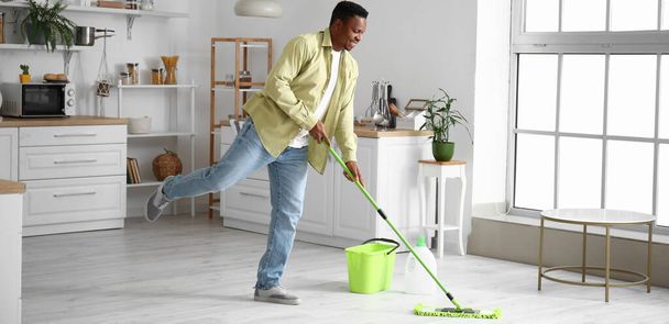African-American man dancing and mopping floor in kitchen - Foto, Imagem