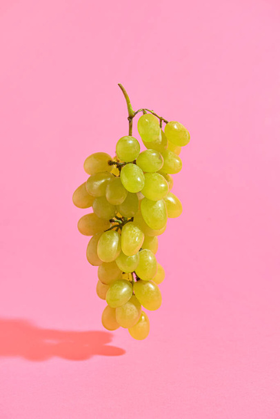 Ripe green grapes on pink background - Fotó, kép