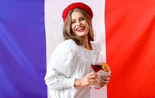 Mulher bonita com croissant e vinho contra a bandeira da França - Foto, Imagem