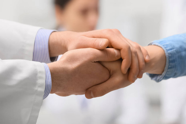 Doctor holding hand of patient in clinic, closeup - Fotoğraf, Görsel