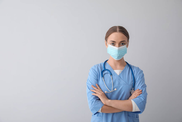 Female nurse in medical mask on grey background - Φωτογραφία, εικόνα