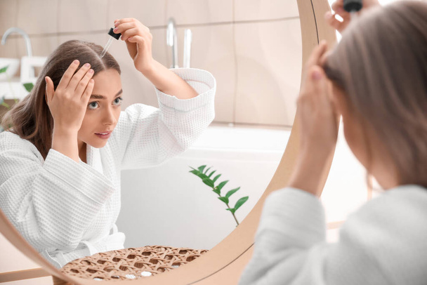 Schöne junge Frau verwendet Serum für das Haarwachstum zu Hause - Foto, Bild