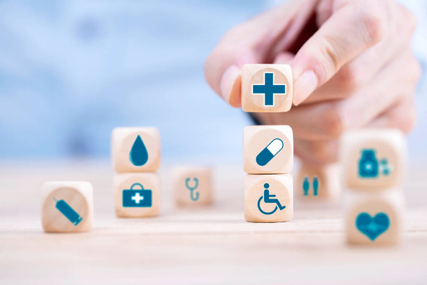 Businessman chooses a emoticon icons healthcare medical symbol on wooden block , Healthcare and medical Insurance concept - Foto, imagen