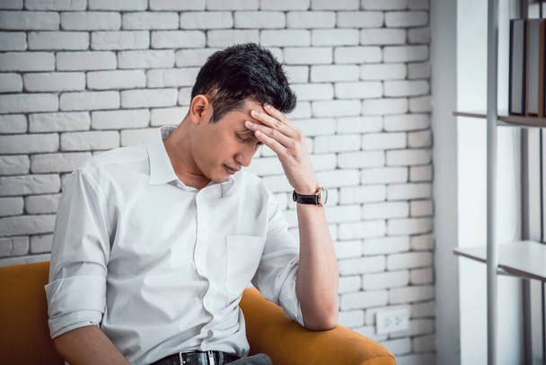 Бізнесмен молодий азіатський має мігрень або головний біль, бореться з запамороченням на сидячому дивані вдома
 - Фото, зображення