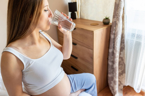 Drinking water pregnant woman. Young pregnancy mother drink water. Pregnant lady waiting of baby. Glass of water. Concept maternity, childbirth - Foto, Bild