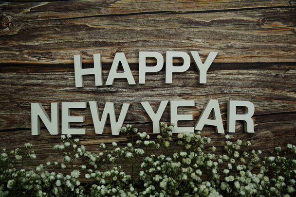 Happy New Year alphabet letters with flowers on wooden background - Photo, Image