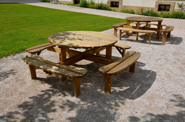 Pergola, puutarhapaviljonki on varustettu metalligrillillä. yleinen grillipaikka puistossa. puutelttapöydät. nurmikko puiston beigen soran ympärillä, uusi, kevät, ympyrä - Valokuva, kuva