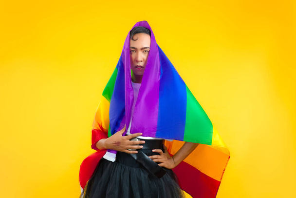 photo of asian gay with pride movement LGBT Rainbow flag isolated yellow background. Man with a gay pride flag - Foto, afbeelding