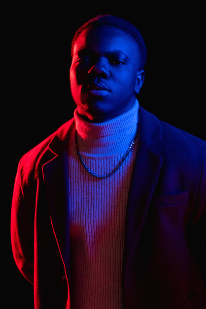 Confident man. Serious face. Neon light portrait. Stylish handsome cyberpunk guy in colorful red blue glow isolated on black background. - Φωτογραφία, εικόνα